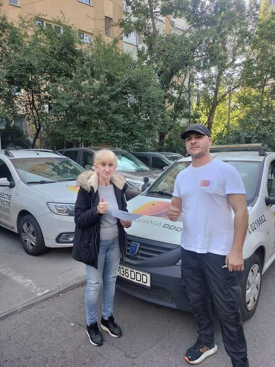 Administratoarea unei asociații de proprietari, cu fișa de lucru în mână, alături de operatorul nostru și două mașini Compania DDD